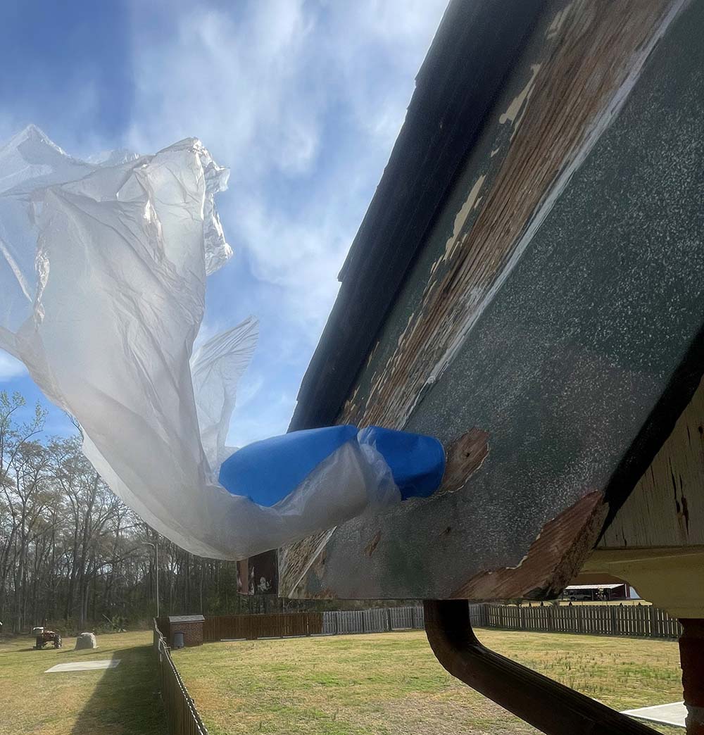 Security camera masked with plastic film during eave scraping and painting in Fayetteville NC
